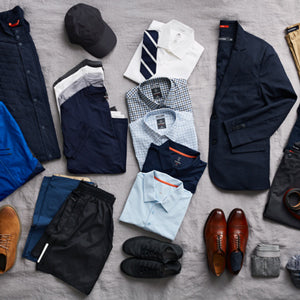 A laydown of mens casual and dress shirts, shoes, blazer, and running clothes on a bed to be packed.