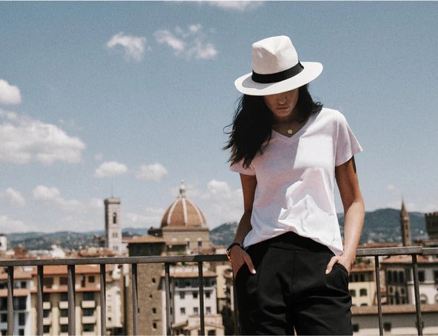 Female model wears a crisp white t-shirt and black travel pants.